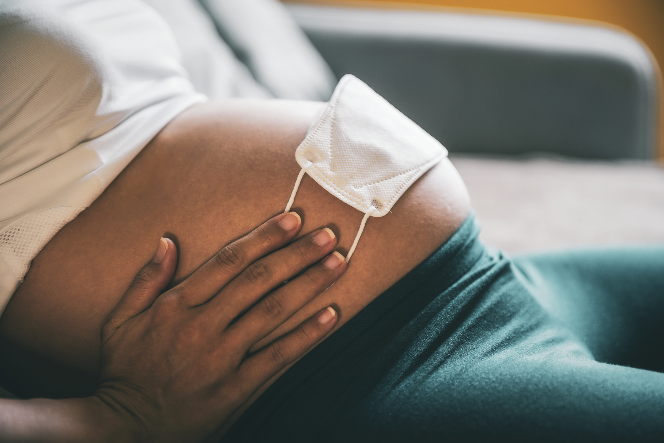 Pregnant woman protecting her baby with a face mask on her belly