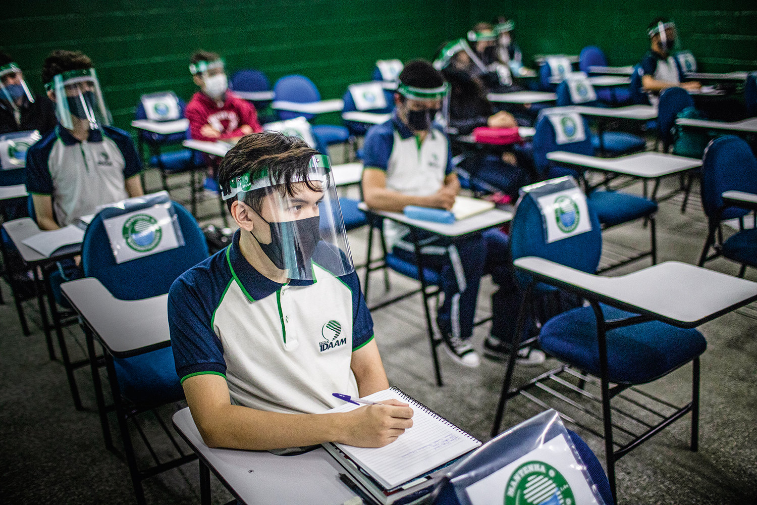 O estudante André Yudji Silva Okimoto, 15, (em primeiro plano) que cursa o 1º Ano do Ensino Médio, assiste a uma aula na unidade em que estuda das Escolas IDAAM, em Manaus, Amazonas, Brasil, em 3 de agosto de 2020, usando máscara respiratória e viseira acrílica, ítens recomendados pela Organização mundial de Saúde (OMS) para frear o contágio da Covid-19 e que são obrigatórios no ambiente escolar. As Escolas IDAAM adotaram diversos procedimentos como aulas presenciais intercaladas com atividades pela internet, o distanciamento entre os alunos, a medição de temperatura, a disponibilização de tótens e garrafas de álcool em gel e o uso obrigatório de viseiras acrílicas e máscaras respiratórias. O Amazonas foi o primeiro estado a permitir o retorno às aulas em unidades de ensino particulares, após a pausa ocasionada pela pandemia da Covid-19. Foto: Raphael Alves / VEJA