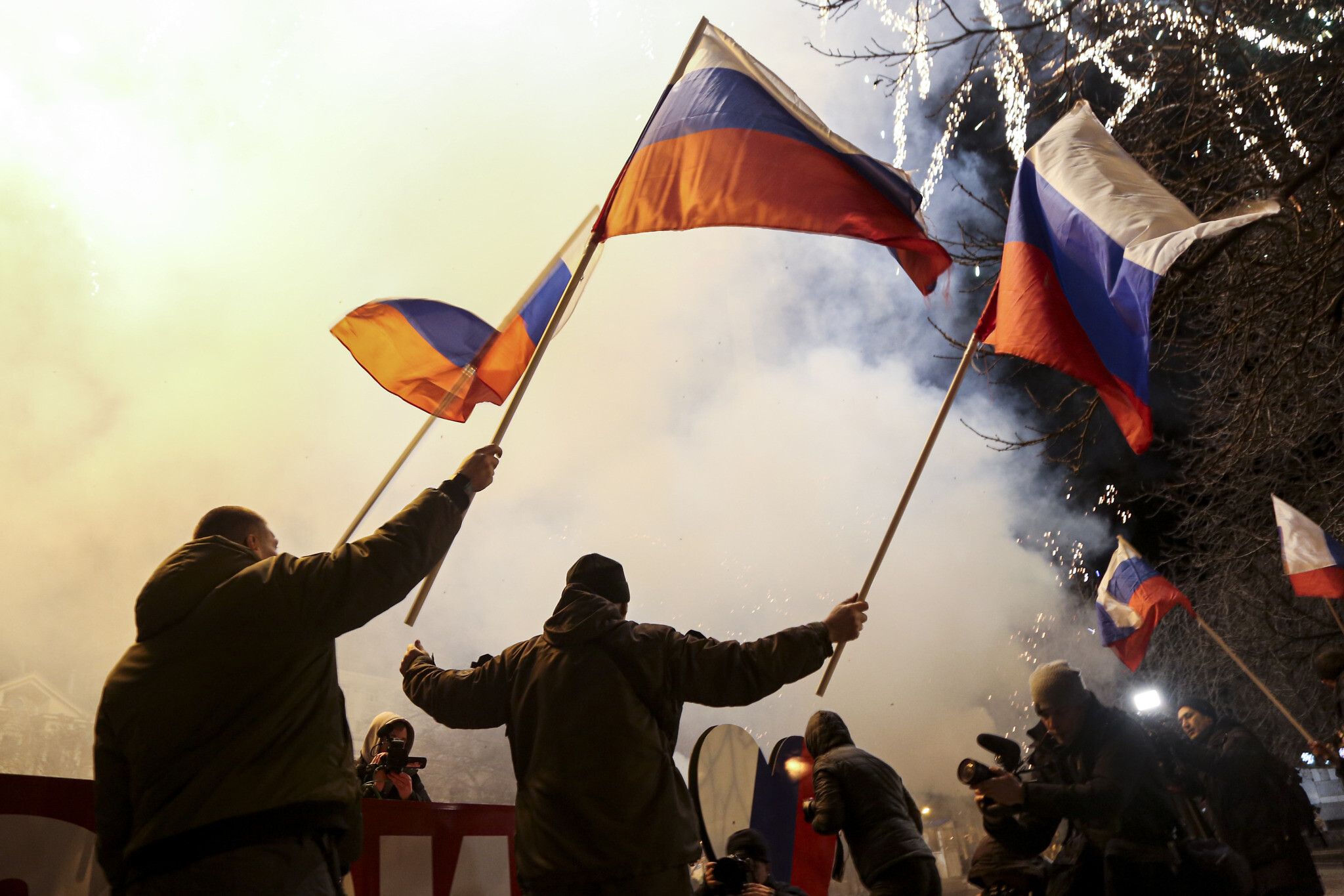 People wave Russian national flags to celebrate, in the center of Donetsk, the territory controlled by pro-Russian militants, eastern Ukraine, late Monday, Feb. 21, 2022. In a fast-moving political theater, Russian President Vladimir Putin has moved quickly to recognize the independence of separatist regions in eastern Ukraine in a show of defiance against the West amid fears of Russian invasion in Ukraine. (AP Photo/Alexei Alexandrov)