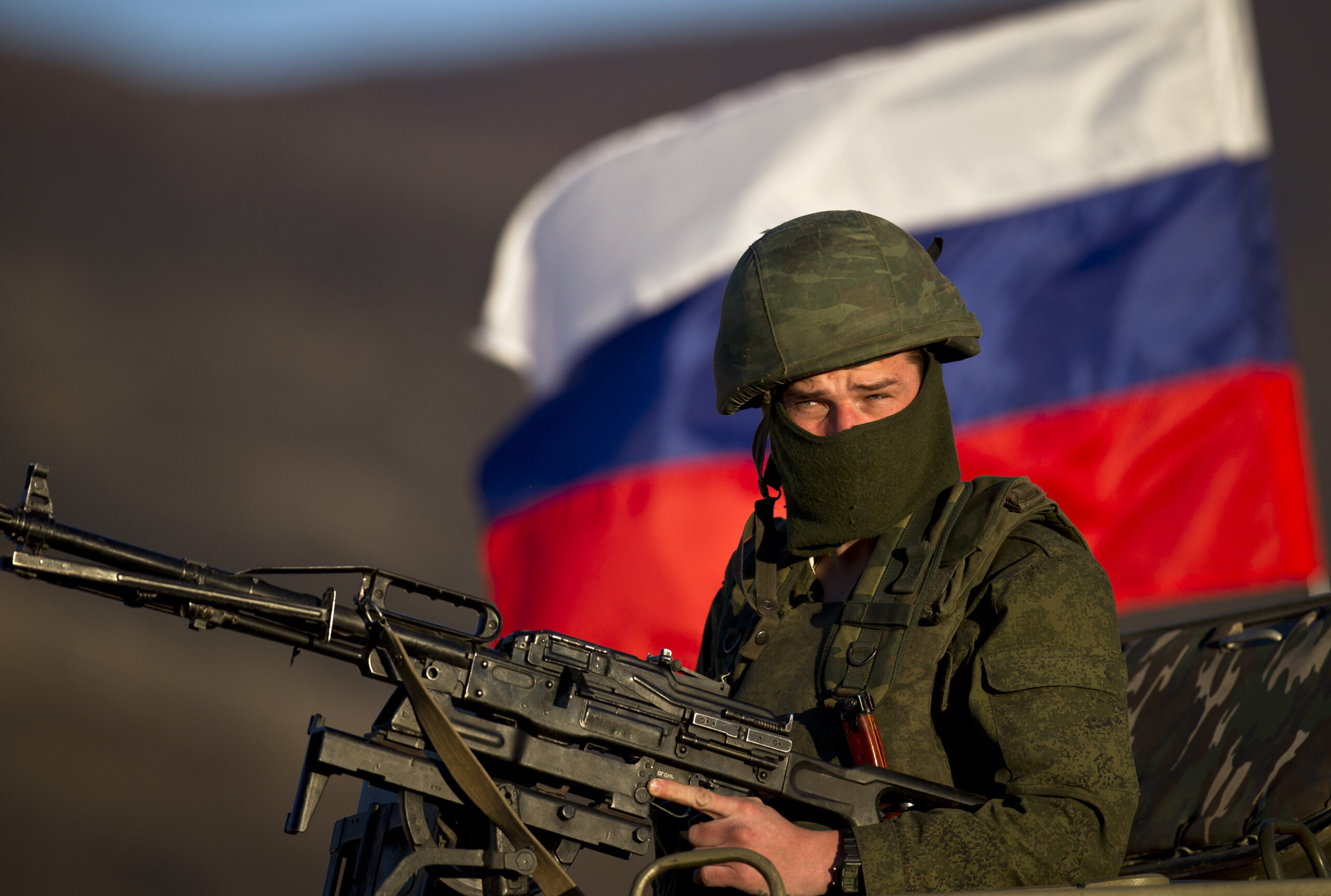 A pro-Russian soldier is back dropped by Russia flag while manning a machine-gun outside an Ukrainian military base in Perevalne, Ukraine, Saturday, March 15, 2014. Tensions are high in the Black Sea peninsula of Crimea, where a referendum is to be held Sunday on whether to split off from Ukraine and seek annexation by Russia. (AP Photo/Vadim Ghirda)