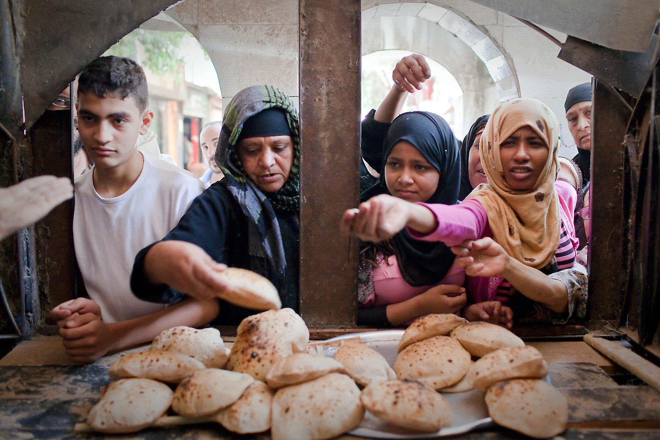 Women buy bread from the window of a bakery in Cairo, Egypt, on Monday, May 20, 2013. Egypt will curb wheat imports by 31 percent to 8 million metric tons in 2012-13, still enough to make it the world's biggest buyer, the U.S. Department of Agriculture estimates. Photographer: Shawn Baldwin/Bloomberg