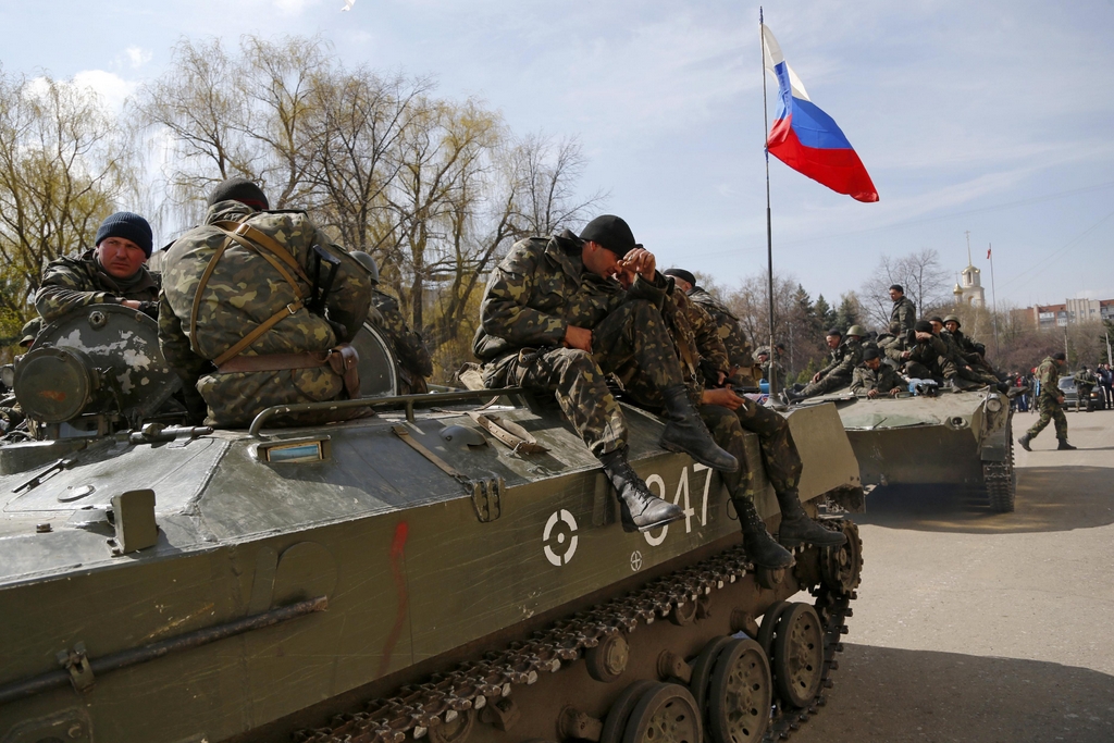 Combat vehicles with a Russian flag on one of them and gunmen on top are parked in downtown of Slovyansk on Wednesday, April 16, 2014. The troops on those vehicles wore green camouflage uniforms, had automatic weapons and grenade launchers and at least one had the St. George ribbon attached to his uniform, which has become a symbol of the pro-Russian insurgency in eastern Ukraine. (AP Photo/ Sergei Grits)