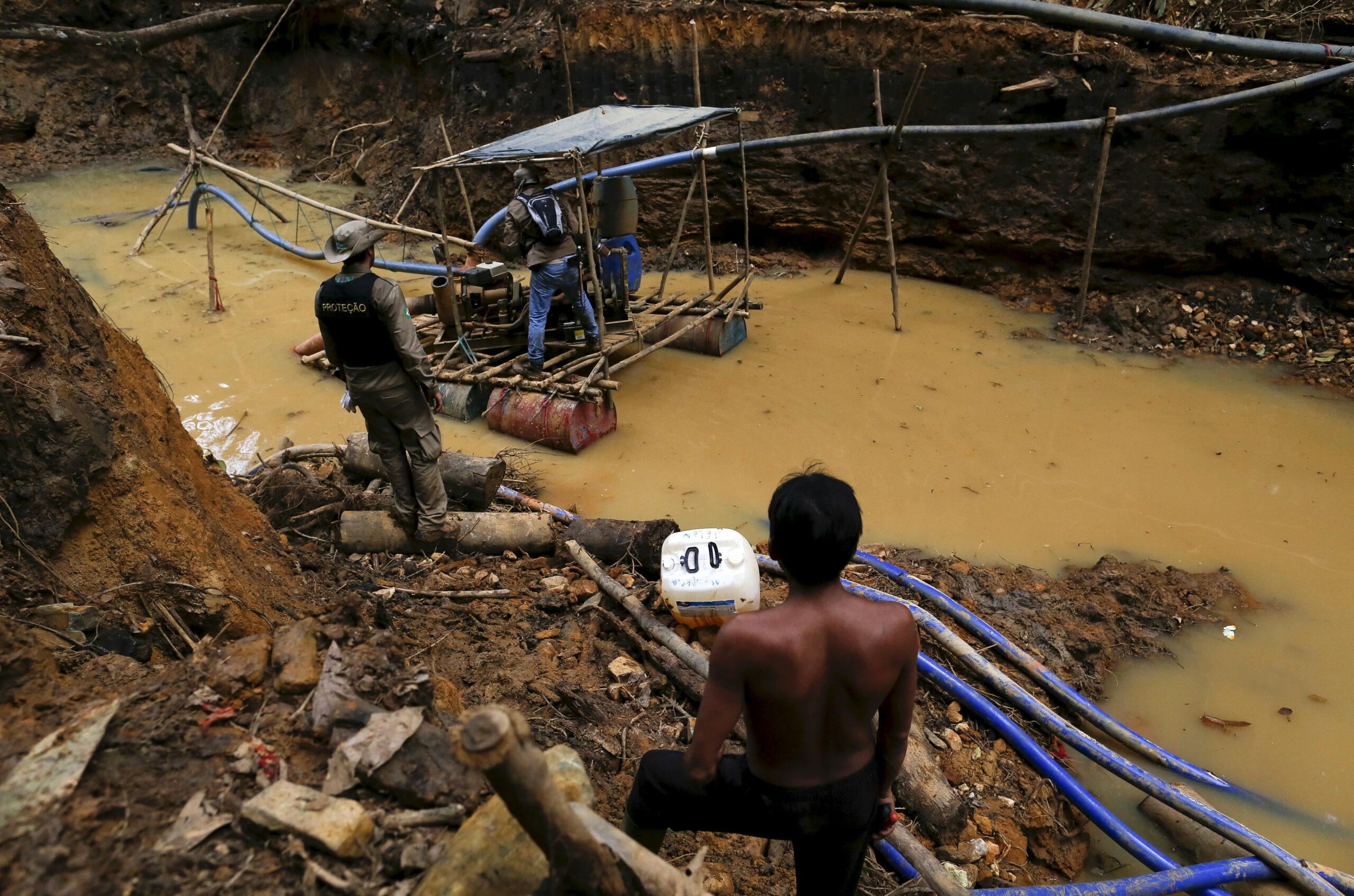 An Yanomami indian (R) stands near an illegal gold mine during Brazil’s environmental agency operation against illegal gold mining on indigenous land, in the heart of the Amazon rainforest, in Roraima state, Brazil April 17, 2016. (Photo by Bruno Kelly/Reuters)